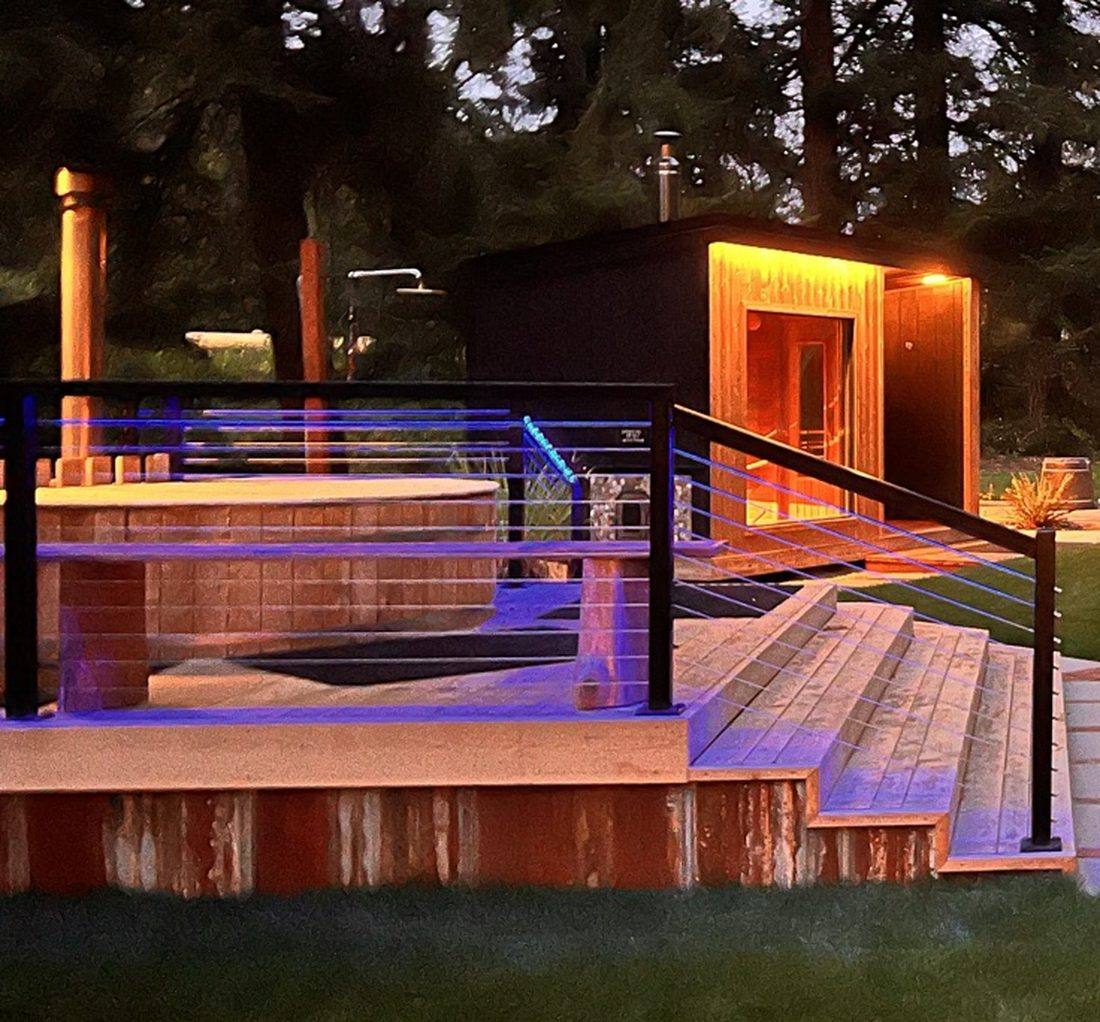 Wood-fired cedar soaking tub on the raised deck at dusk