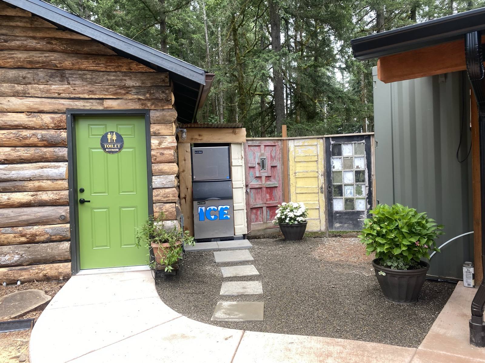 Log cabin with green door, vintage-door fence, and ice machine