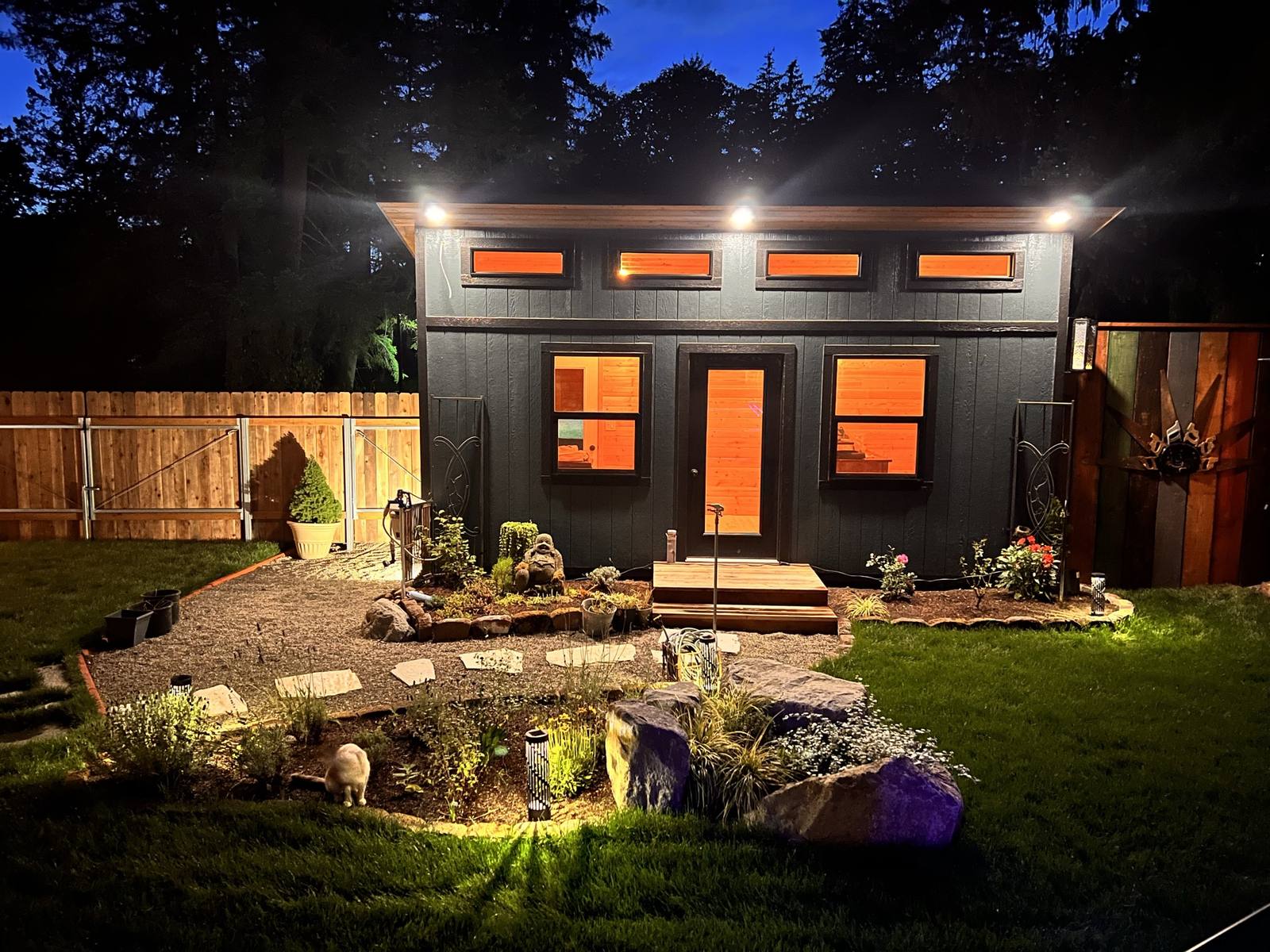 The office glowing at night behind the landscaped rock garden