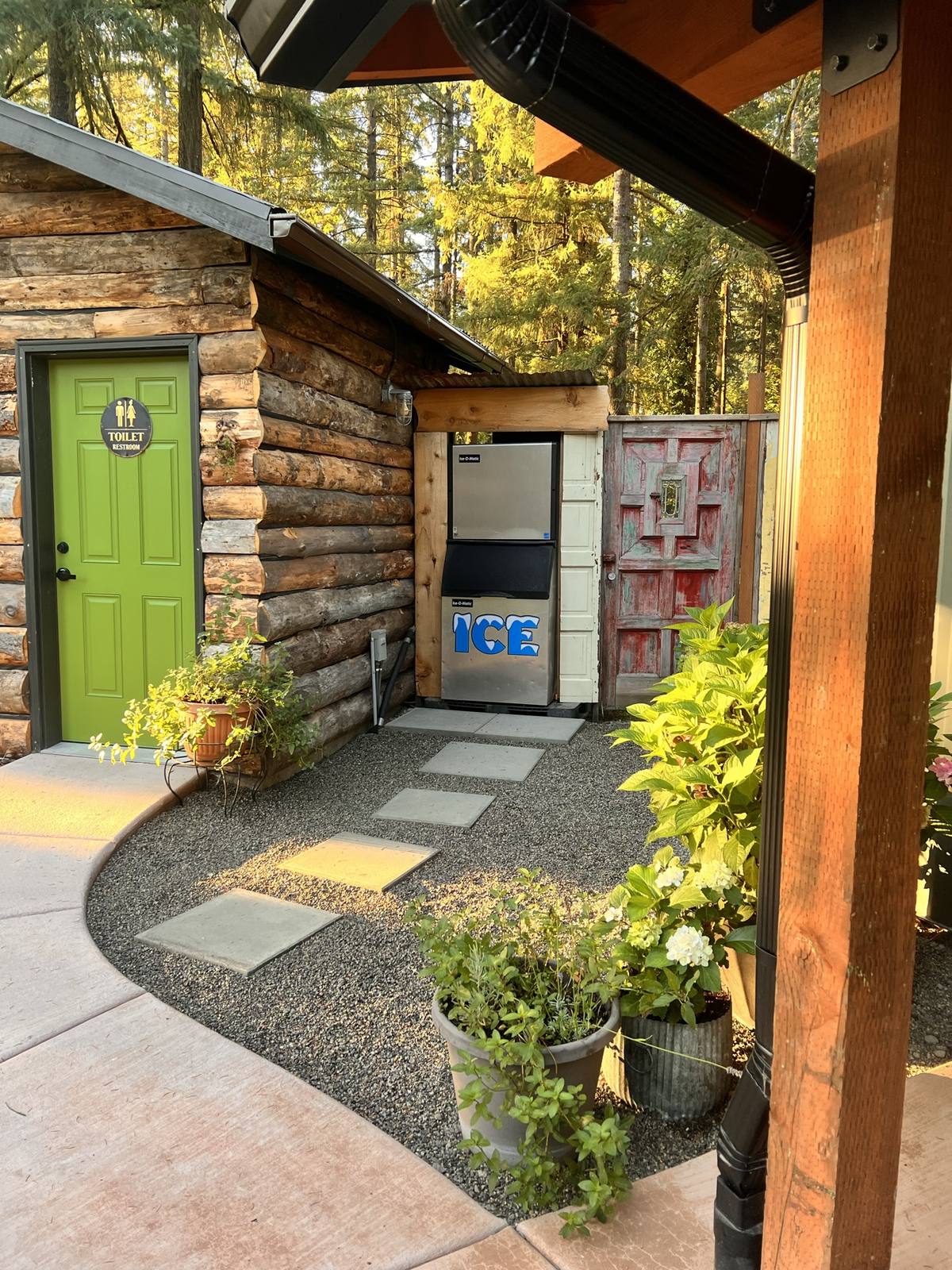 Log cabin restroom and ice machine off the gravel path